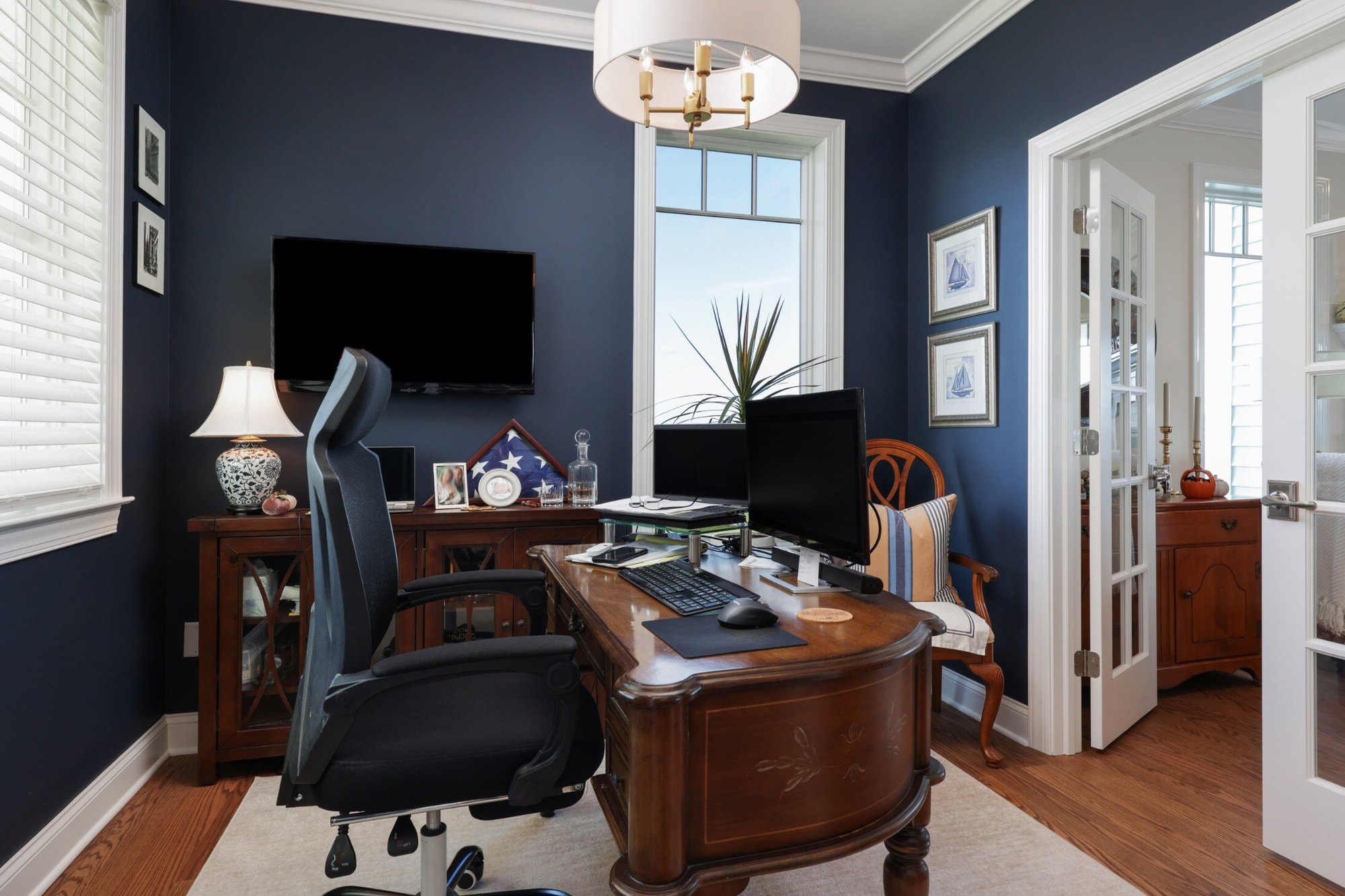 Close-up of a well-appointed home office in a custom home by GTG Builders in Brick, NJ, with a dark blue accent wall, traditional desk, and large windows