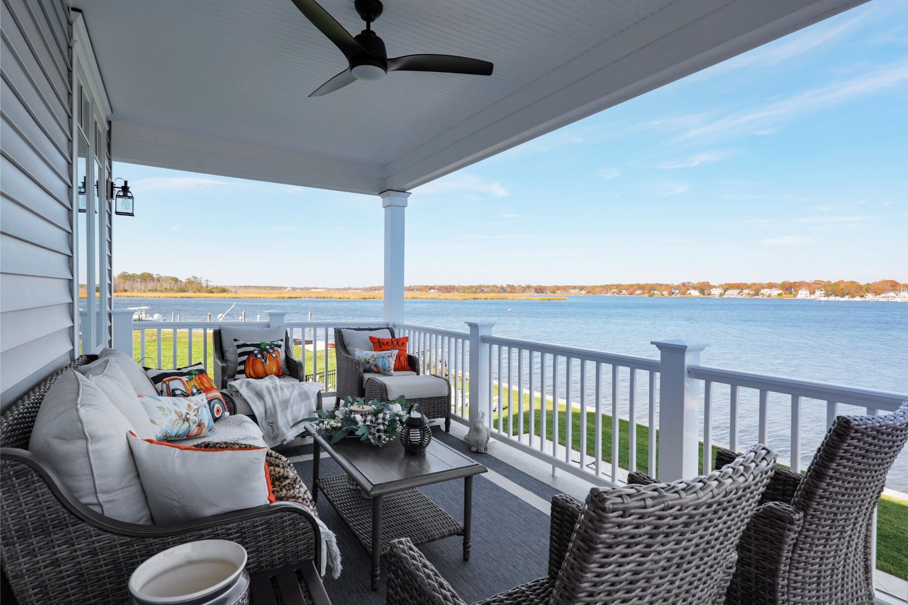 Covered outdoor porch with cozy seating, fan, and waterfront views in a custom home by GTG Builders in Brick, NJ