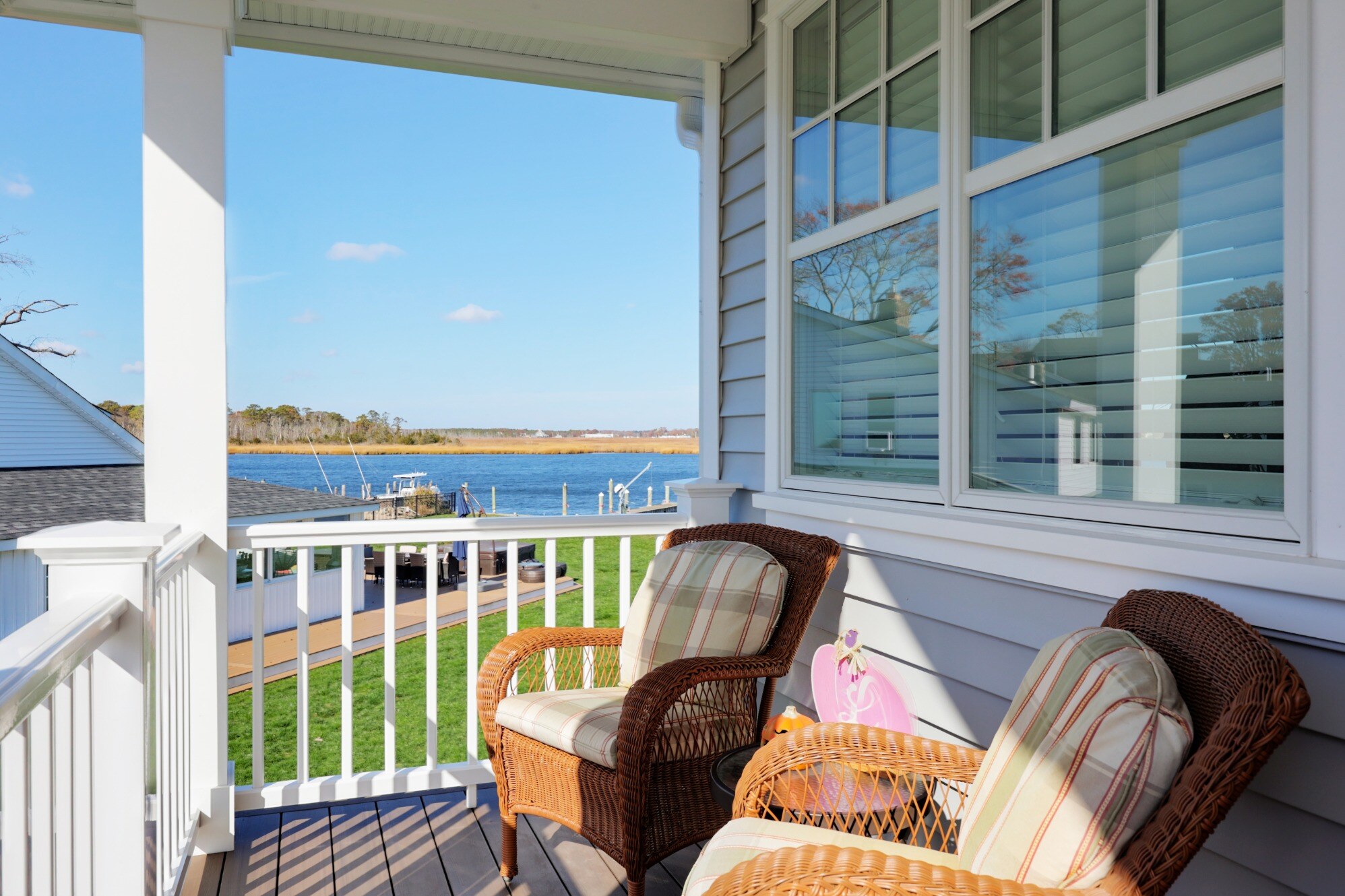 Cozy balcony seating with wicker chairs overlooking the water at a custom home by GTG Builders in Brick, NJ