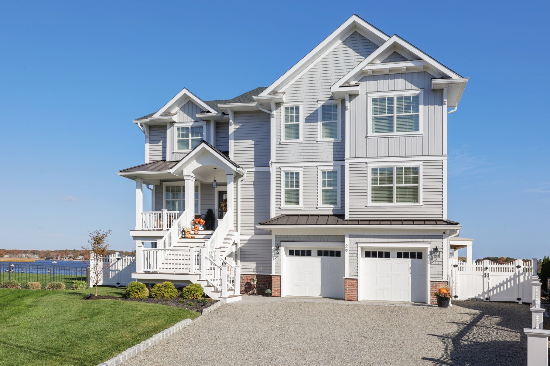 Full exterior shot of a custom home by GTG Builders in Brick, NJ, with a spacious driveway, double garage, and welcoming front porch decorated for fall
