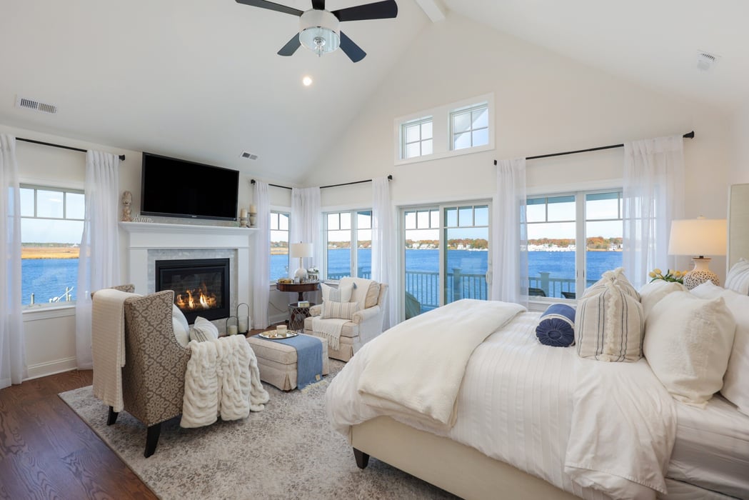 Master bedroom with fireplace, large windows, and waterfront views in a custom home by GTG Builders in Brick, NJ