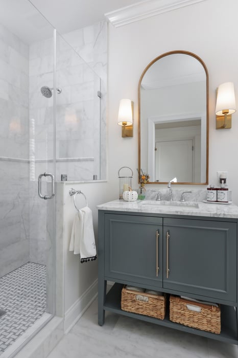 Modern bathroom with marble shower, dark gray vanity, and gold accents in a custom home by GTG Builders in Brick, NJ