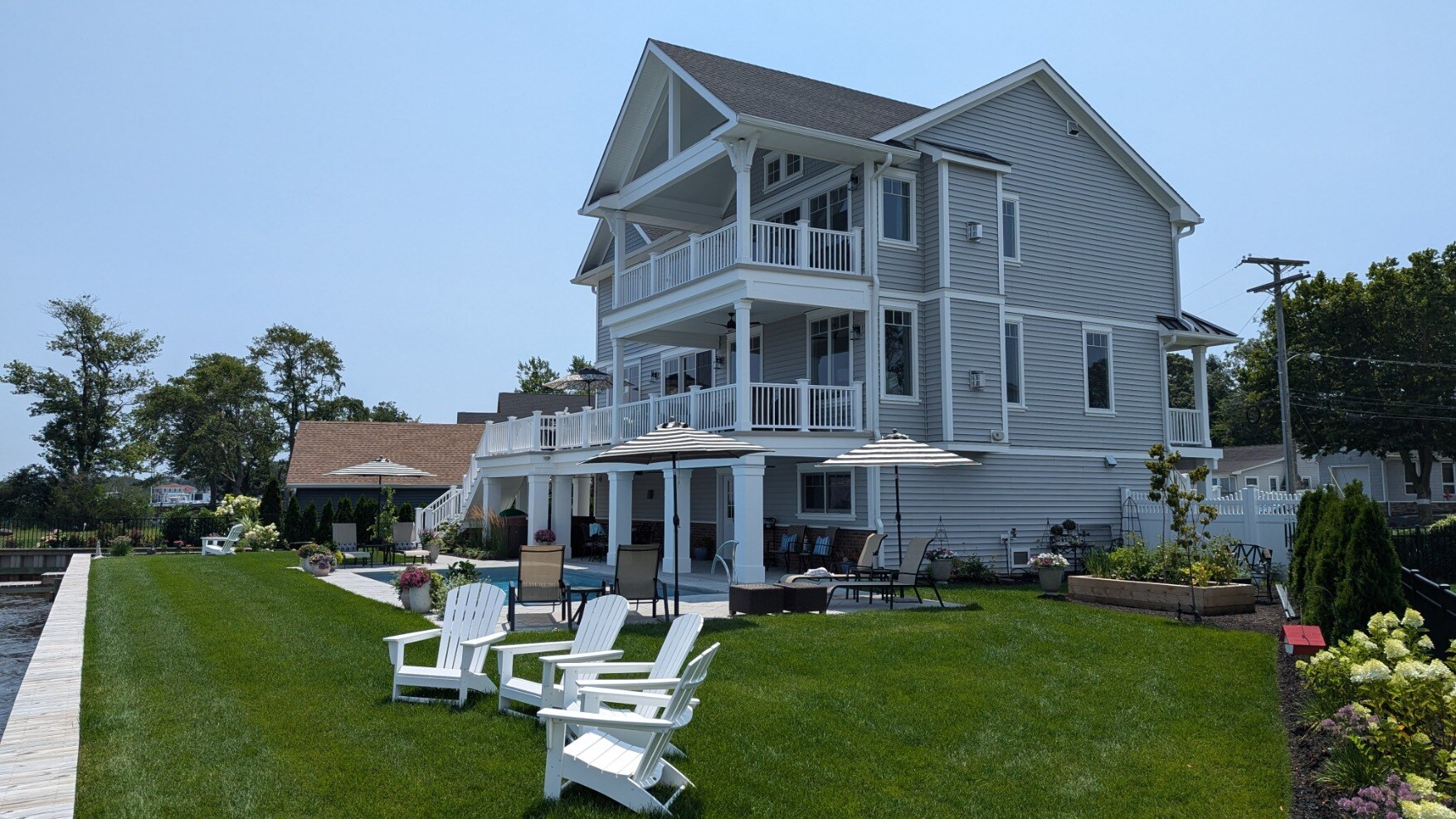 Side view of a new custom waterfront home by GTG Builders in Brick, NJ, featuring balconies, patio seating, and a beautifully landscaped yard-1