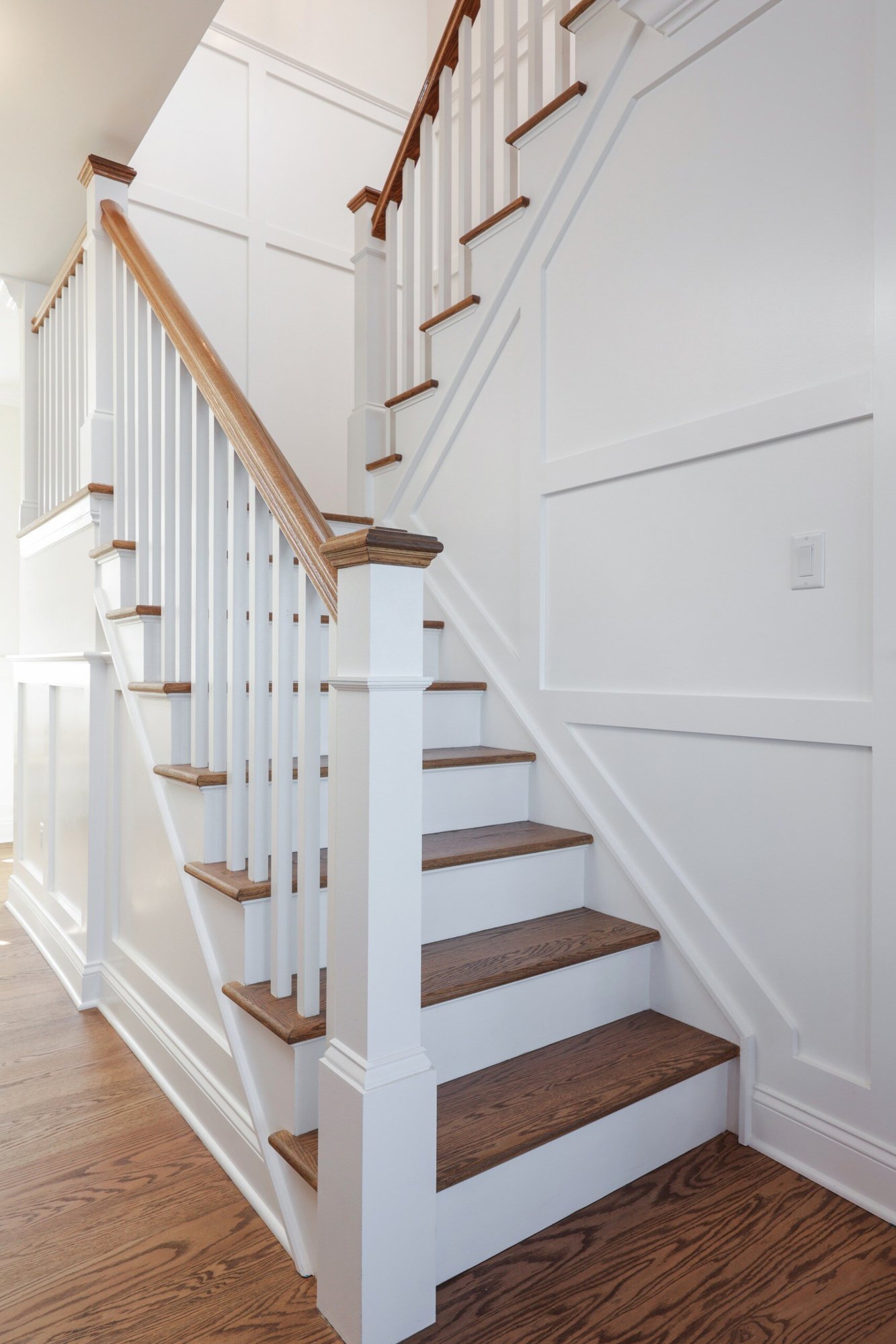Staircase with white wainscoting and wooden handrails in a custom home by GTG Builders in Brick, NJ