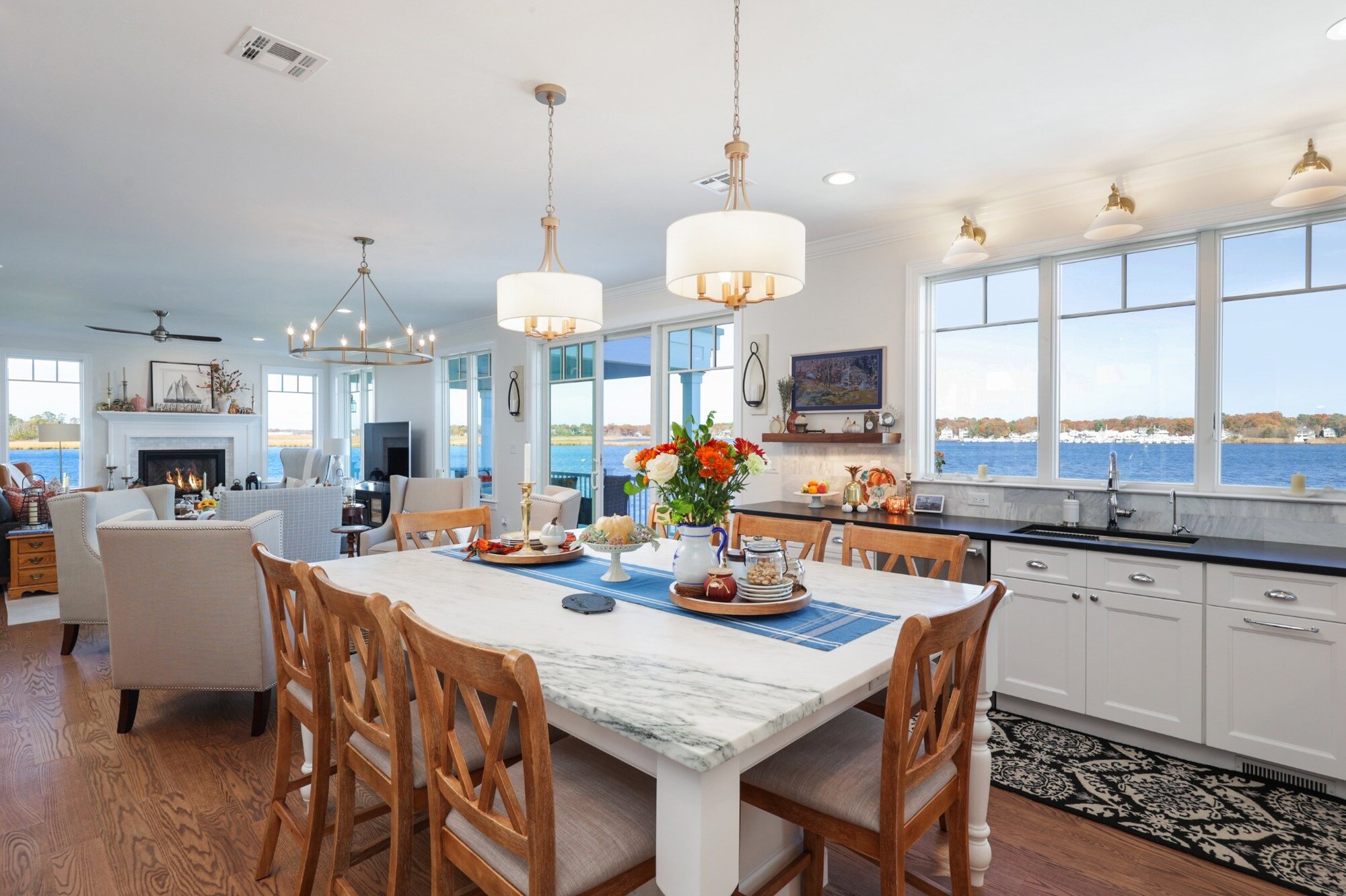 View from the kitchen into the living and dining areas with waterfront windows in a custom home by GTG Builders in Brick, NJ