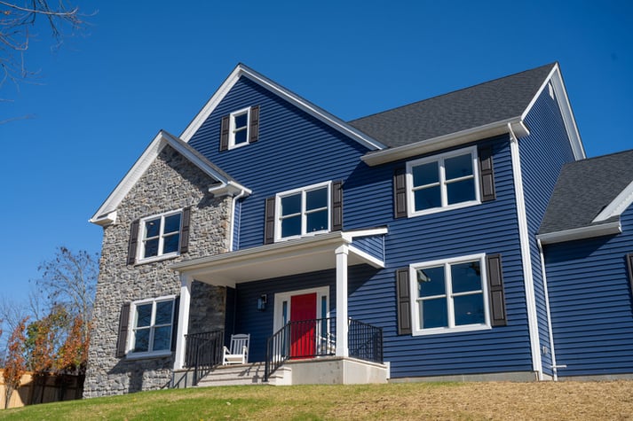 custom home with blue and stone exterior with red door bGTG Builders in Central New Jersey