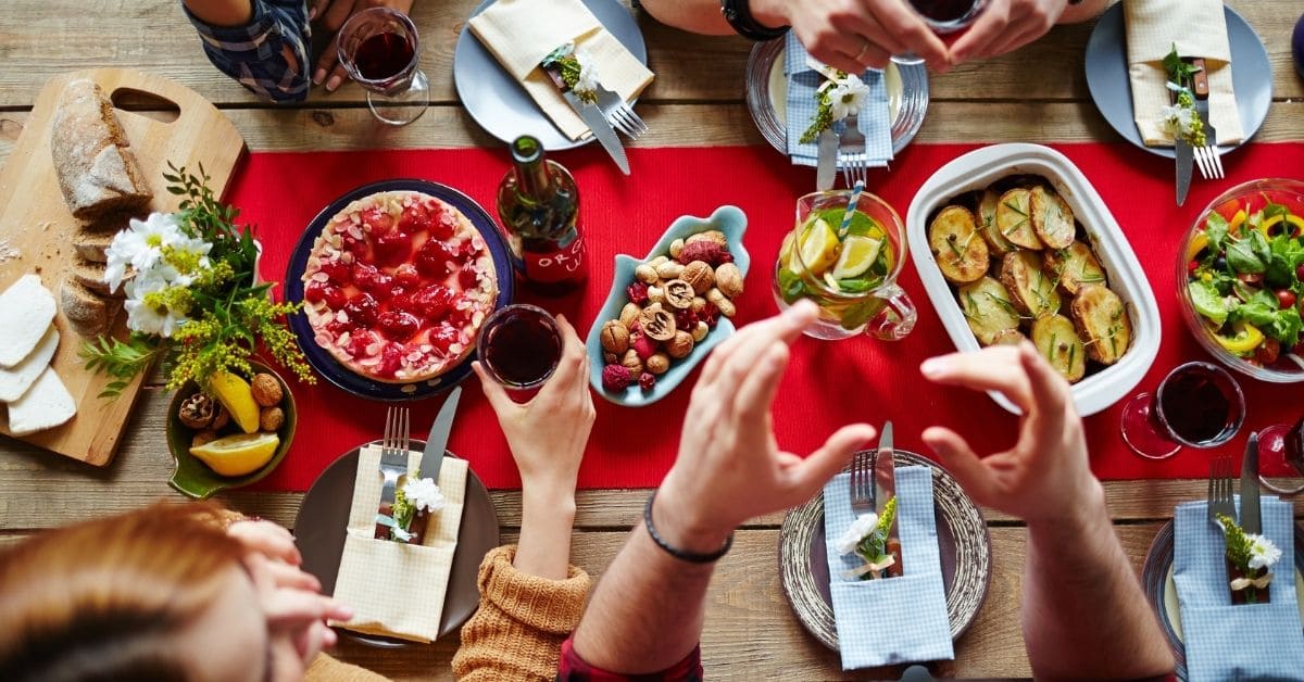 festive holiday table with red table runner and people surrounding table