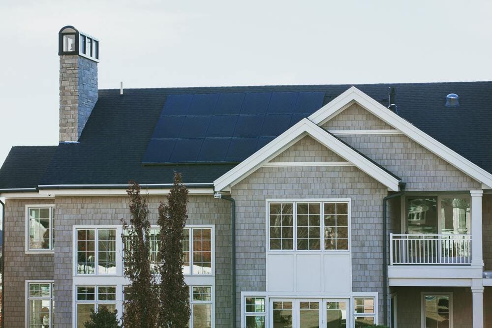 Vivint Solar - Solar Panels on a large seaside home with chimney and many windows.