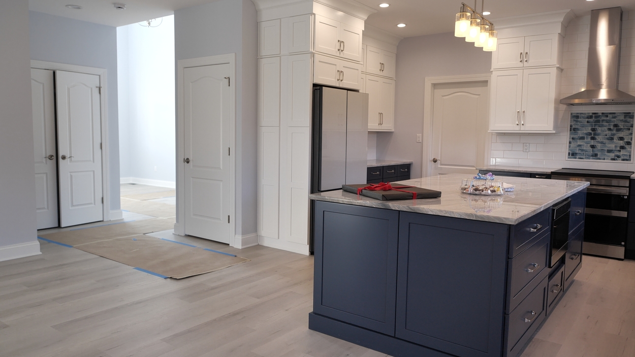 Kitchen island with marble countertop and surrounding white cabinetry in a net-zero custom home in Bloomsbury, NJ by GTG Builders