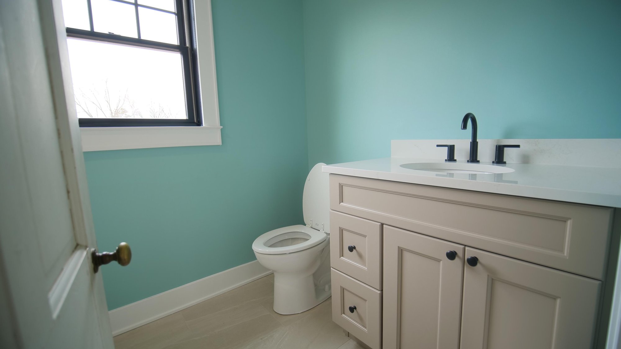 light teal bathroom with white marble countertop and beige vanity and black features by gtg builders in pittstown