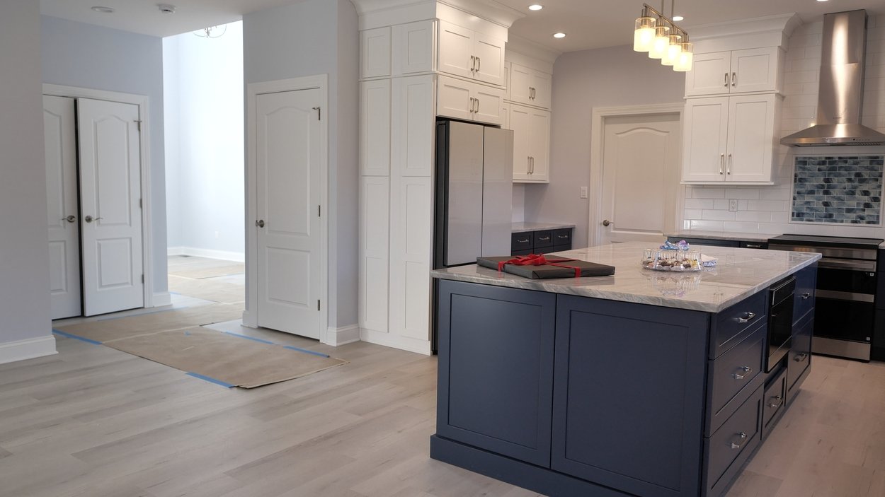Kitchen island with marble countertop and surrounding white cabinetry in a net-zero custom home in Bloomsbury, NJ by GTG Builders