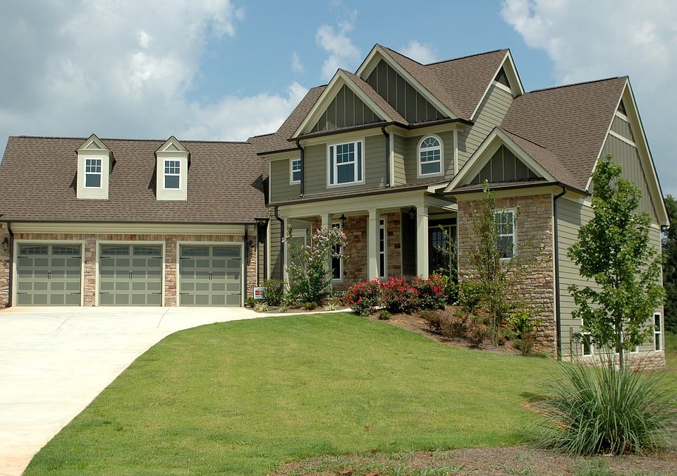 brown house with 3 garage doors and brick exterior