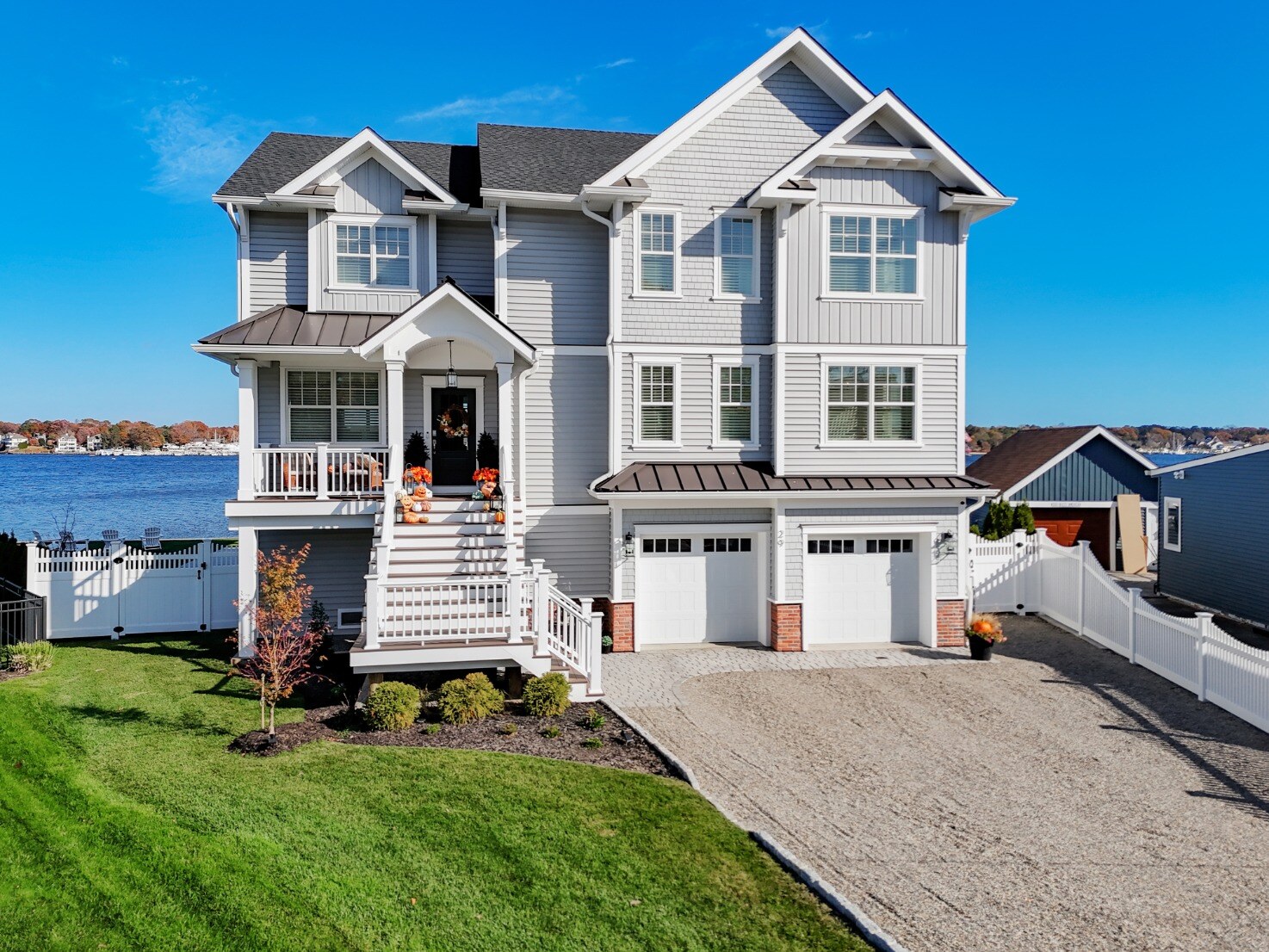 Front view of GTG Builders’ custom three-story home in Brick, NJ, with a dual garage, inviting front porch, and Halloween decorations
