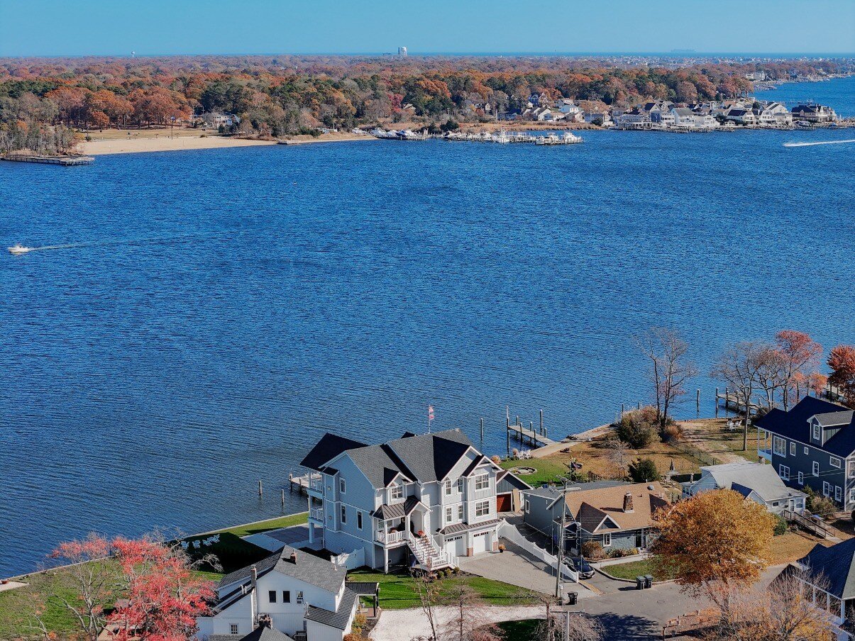 Wide aerial view of a waterfront community with GTG Builders custom home in Brick, NJ, highlighting its prime waterfront position and dock