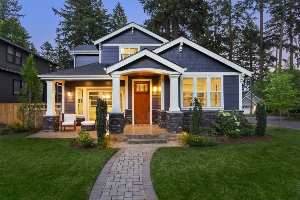 Exterior custom-built grey-blue home with stone walkway leading to front door