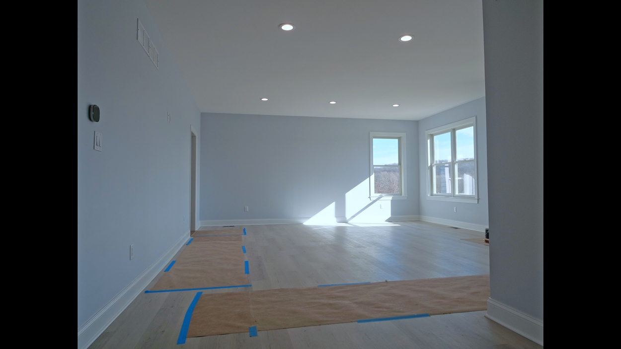 Minimalist primary bedroom with light hardwood floors and recessed lighting in a net-zero custom home in Bloomsbury, NJ by GTG Builders