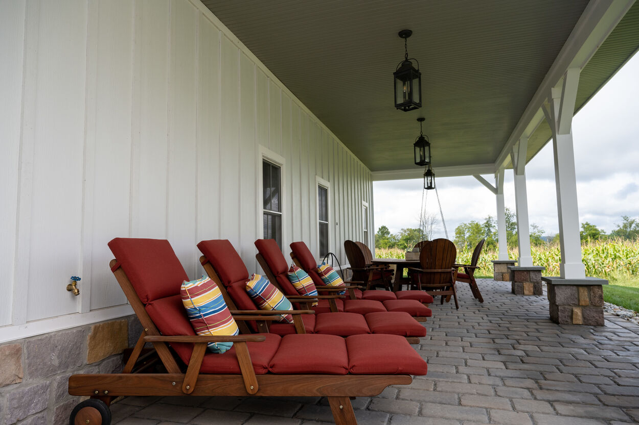 covered porch with red seating by GTG Builders in Stockton, New Jersey