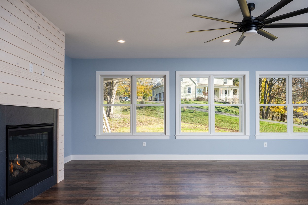 living space with fireplace, ceiling fan, and blue walls with windows in custom home by GTG Builders in Central New Jersey