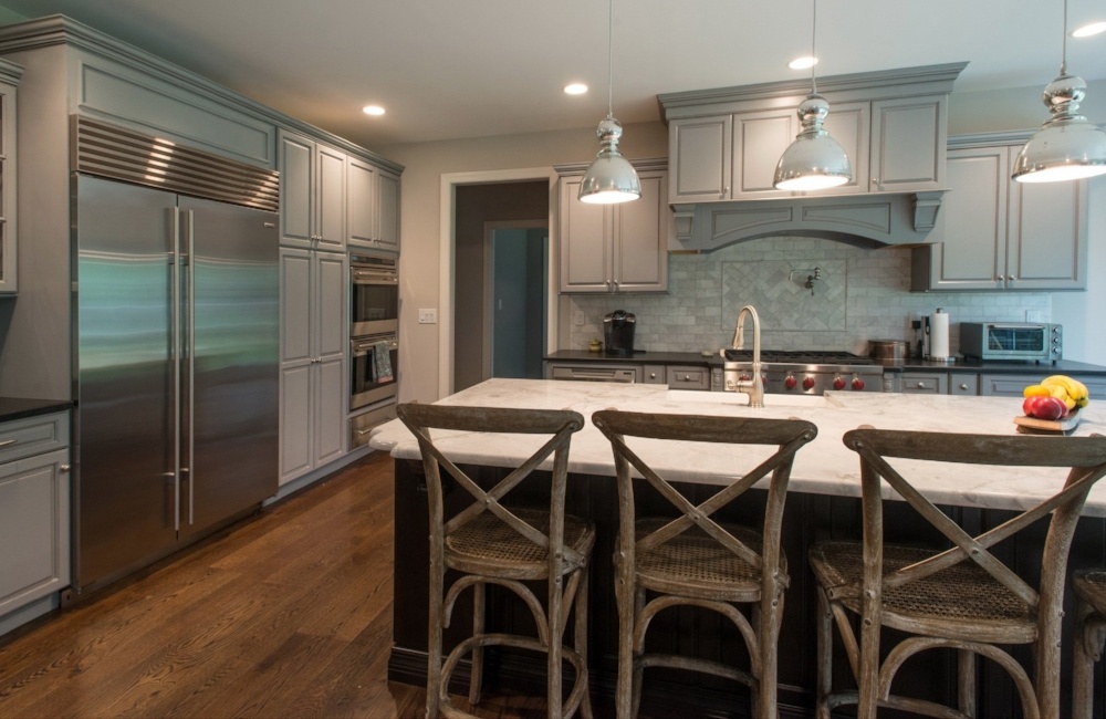 kitchen with white island, grey cabinets, and large refrigerator in custom home by gtg builders in central new jersey